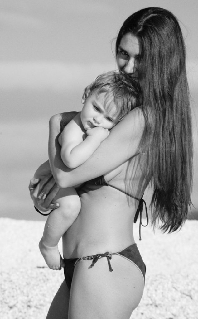 Confident mother in a bikini holding a baby